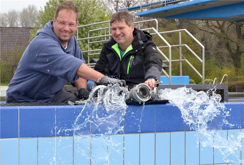 Andreas Bockelmann (links) und Betriebsleiter Michael Wege drehen den Hahn auf. Jetzt kann das Nichtschwimmerbecken volllaufen.  Foto: Fehlbus