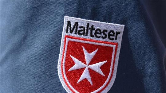 Das Logo der Malteser ist an der Jacke eines Helfers zu sehen.