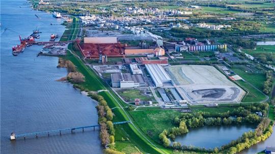 Der Industriepark auf Bützflethersand: Im Vordergrund die Flächen, auf denen das Holzkraftwerk entstehen soll, dahinter die AOS mit ihren roten Steinbergen; direkt links davon der Seehafen.