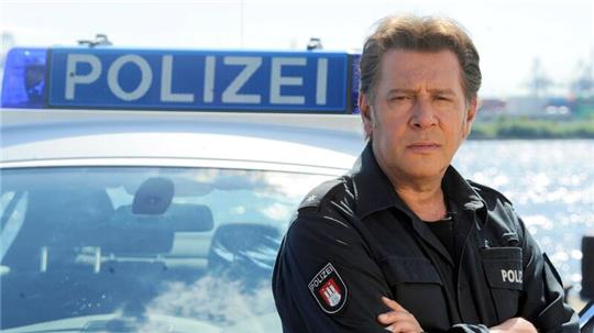 Der Schauspieler Jan Fedder steht bei einem Fototermin zum „Großstadtrevier“ an einem Polizeiwagen.
