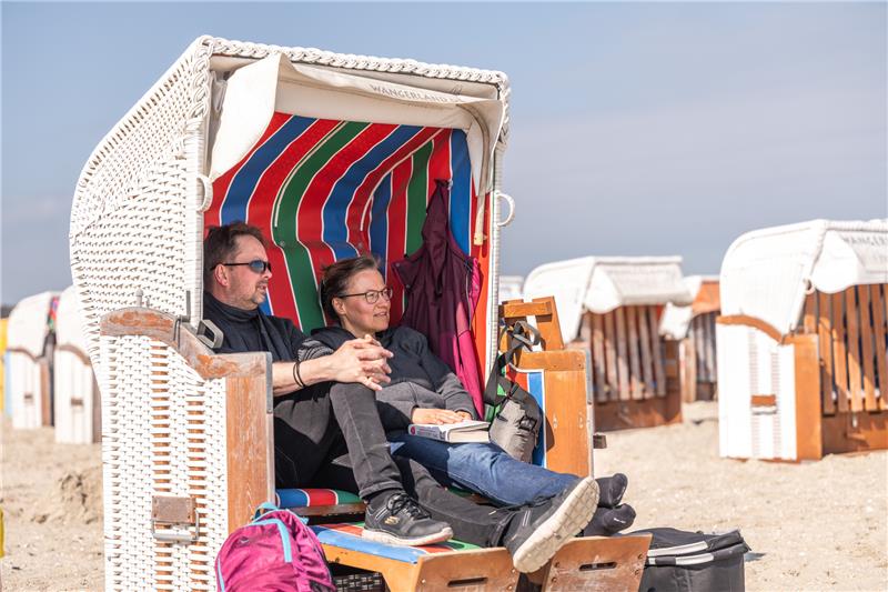 Die Urlauber Elisabeth und Julius aus Nordrhein-Westfalen sitzen bei schönem Wetter in einem Strandkorb am Nordseestrand von Schillig. Foto: Mohssen Assanimoghaddam/dpa