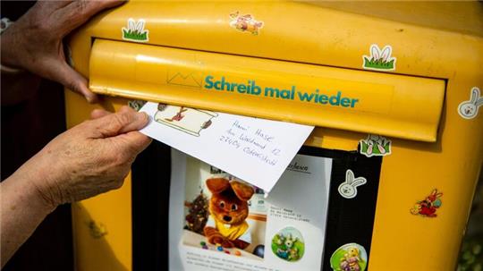 Ein Brief, den ein Kind für den Osterhasen geschrieben hat, wird in einen Briefkasten geworfen.