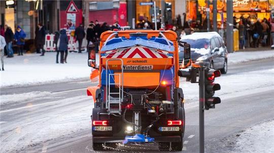 Ein Fahrzeug vom Winterdienst fährt in der Innenstadt über den Jungfernstieg und streut die Straße.