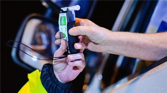 Ein Polizist reicht einem Lastwagenfahrer ein Alkoholmessgerät in die Fahrerkabine.