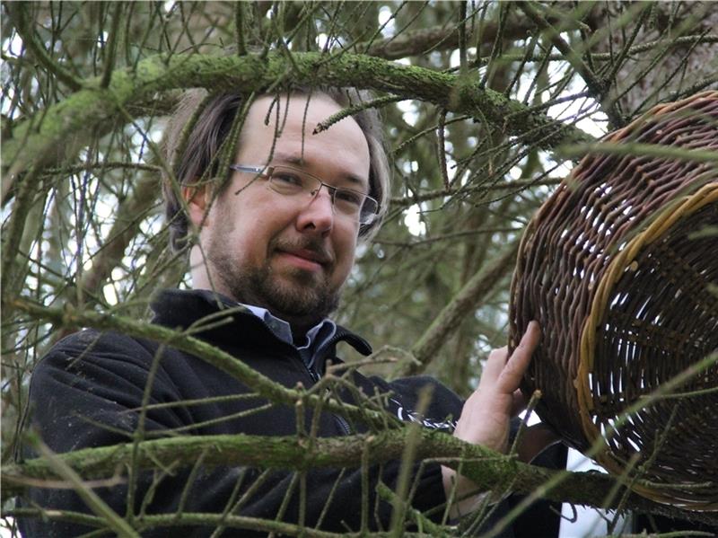 Hans Dietrich bringt an einem Baum am Friedhof einen Weidenkorb als Nistmöglichkeit an.