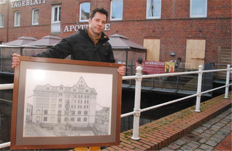 Intermezzo-Inhaber John Gawen-Chinellato zeigt eine Zeichnung der Fleth-Mühle. Diese zeigt das Baudenkmal in den 1950er Jahren. In den Arkaden werden jetzt Fenster eingesetzt, das Lokal wird erweitert.  Foto Vasel