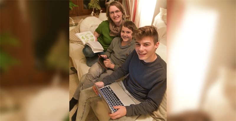 Katrin Richter und ihre Söhne haben es sich mit ihren Lieblings-Medien auf dem Sofa gemütlich gemacht: Die Mutter mit einem Buch, der 12-jährige Theo mit dem Handy und der 17-jährige Marwen mit seinem Laptop.