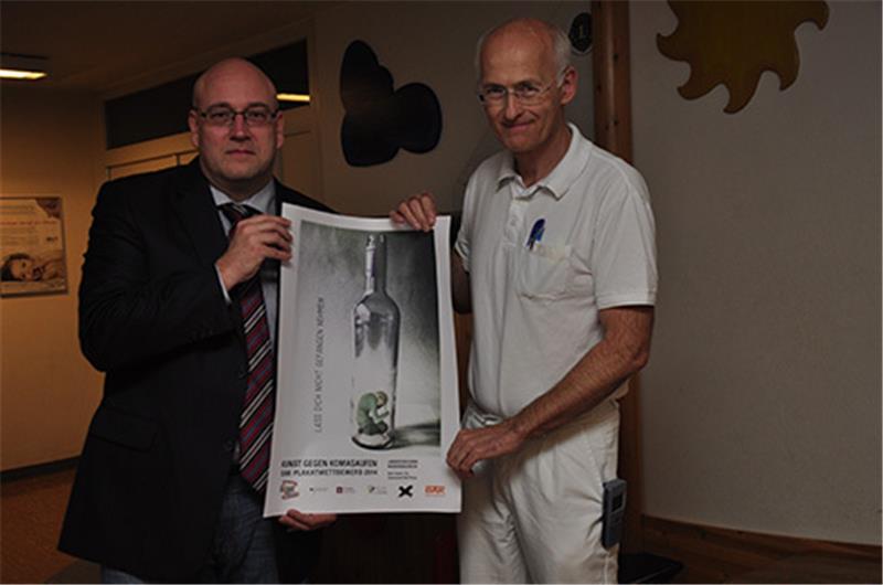 Matthias Herzberg (links) und Dr. Volker Berg mit dem Sieger-Plakat aus Niedersachsen des DAK-Wettbewerbs „bunt statt blau“ von Nele Daske (15). Foto Strüning