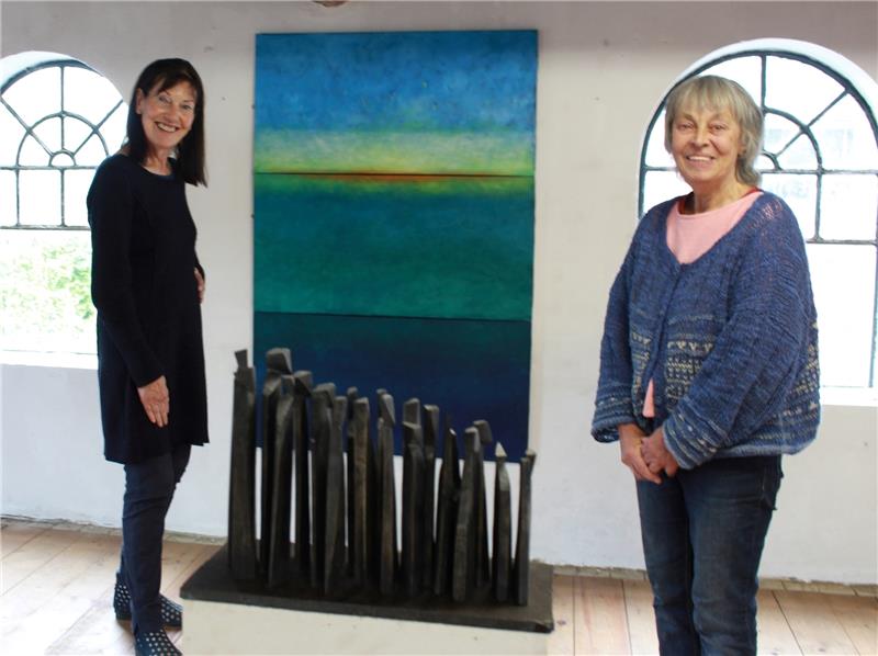 Monika Linnert (links) mit ihrem Gemälde „Lichter Horizont“. Davor ist die Skulptur „Unterwegs I“ der Holzbildhauerin Barbara Uebel (rechts) zu sehen. Weitere Arbeiten zeigen sie am Wochenende. Foto Richter