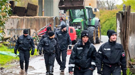 Polizisten gehen auf der Suche nach dem vermissten Arian über ein landwirtschaftliches Gelände.