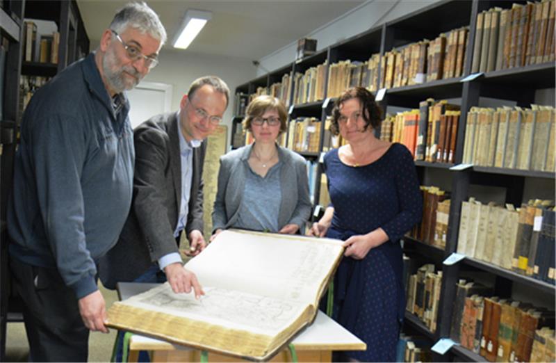 Historische Bibliothek am Gymnasium Athenaeum wird katalogisiert Präsentieren einen dicken Atlas aus dem 17. Jahrhundert: Forscher Peter van der Krogt aus Amsterdam, auf einem Besuch in Stade, und die Lehrkräfte Lars Hellwinkel und Andrea Helmers zusammen mit Bibliothekarin Catrin Gold vom Landschaftsverband im Gymnasium Athenaeum. Foto: Beneke