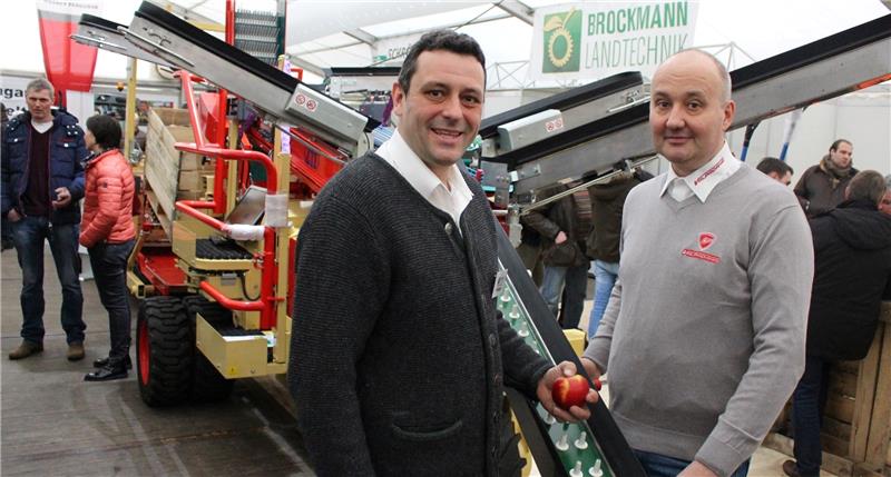 Wie Arme ragen sechs Pflückbänder aus der Erntemaschine: Peter Brockmann (links) vertreibt sie in Jork, Mario Schmidt importiert sie aus Italien.