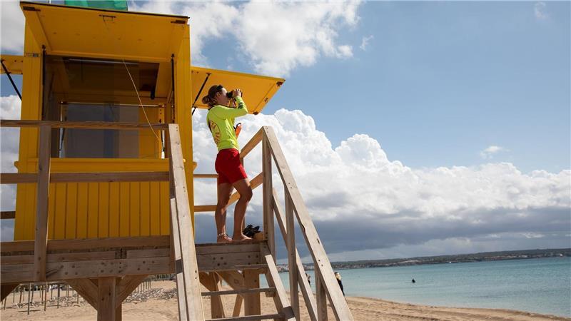  Ein Rettungsschwimmer benutzt ein Fernglas, während er am Strand von Palma auf Mallorca patrouilliert. 