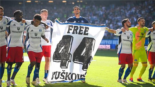  Hamburgs Spieler jubeln nach dem Sieg vor den eigenen Fans und halten dabei ein Transparent mit der Aufschrift "Free 44 Vuskovic" und stellen sich damit hinter den gesperrten Mitspieler.