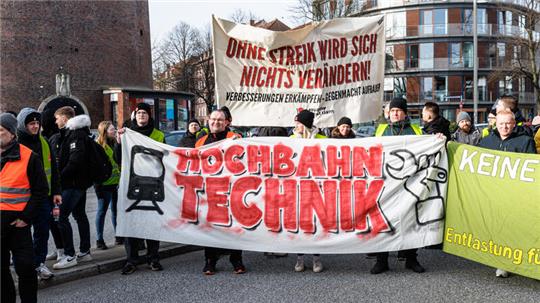  Hochbahnmitarbeiter stehen hinter einem Transparent mit der Aufschrift „Ohne Streik wird sich nichts verändern“.