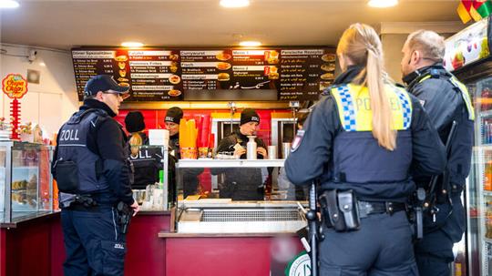 12.12.2023, Hamburg: Einsatzkräfte von Polizei, Zoll und Behörden stehen im Stadtteil Rothenburgsort in der Billstraße in einem Imbiss. Bei einer großangelegten Aktion sind in der Hamburger Billstraße ein Dutzend Gaststätten, Imbisse und ähnliche gastronomische Betriebe durchsucht worden. Foto: Daniel Bockwoldt/dpa - ACHTUNG: Teile des Bildes wurde(n) aus rechtlichen Gründen gepixelt +++ dpa-Bildfunk +++