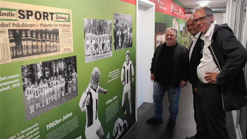 20 Meter voller Geschichte: Vereinschef Lutz Becker, Fußball-Abteilungsleiter Thorsten Friese und Pressesprecher Thomas Butter (von links) schauen sich die Wand der Legenden an.