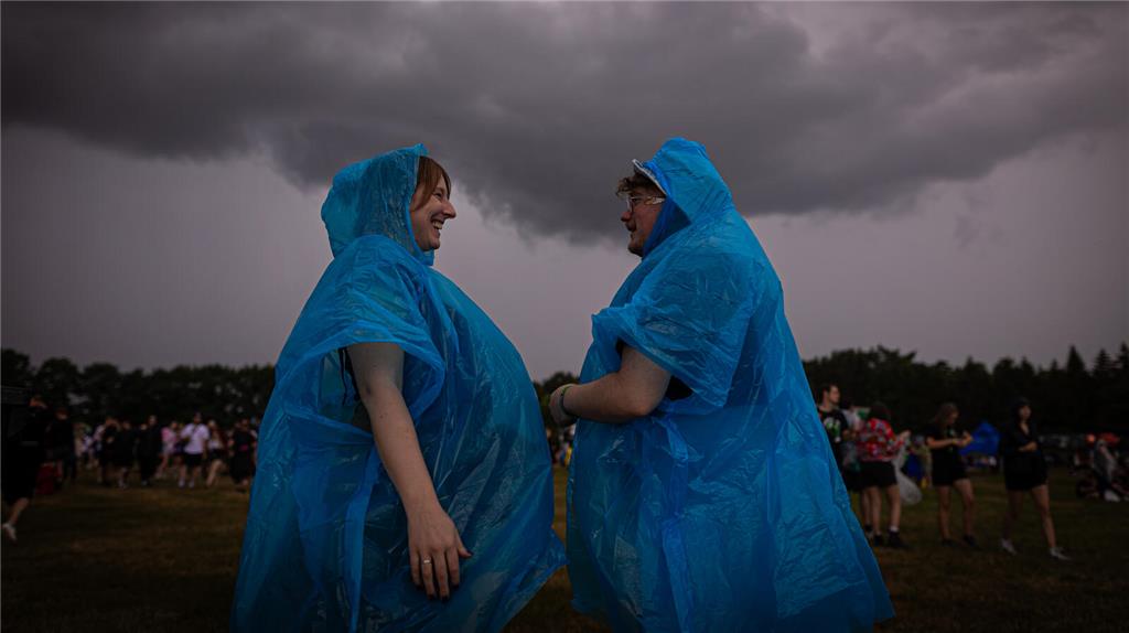 21.06.2024, Niedersachsen, Scheeßel: Zwei Festivalbesucher tragen Regenponchos, ...