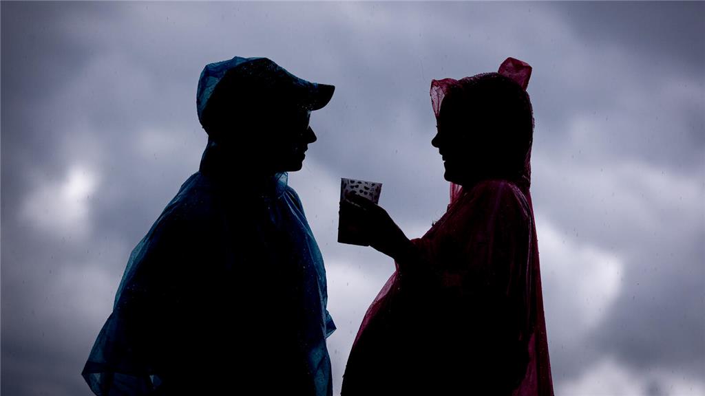 21.06.2024, Niedersachsen, Scheeßel: Zwei Festivalbesucher tragen Regenponchos, ...
