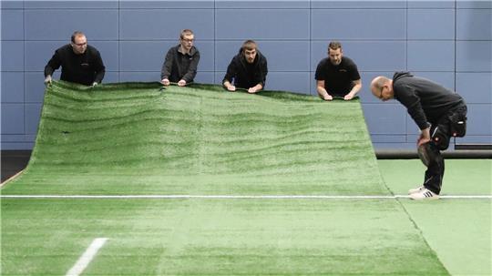 22 Meter lang und 4 Meter breit sind die Kunstrasenstücke, die die Firma Scholz im Sportcampus verlegt.