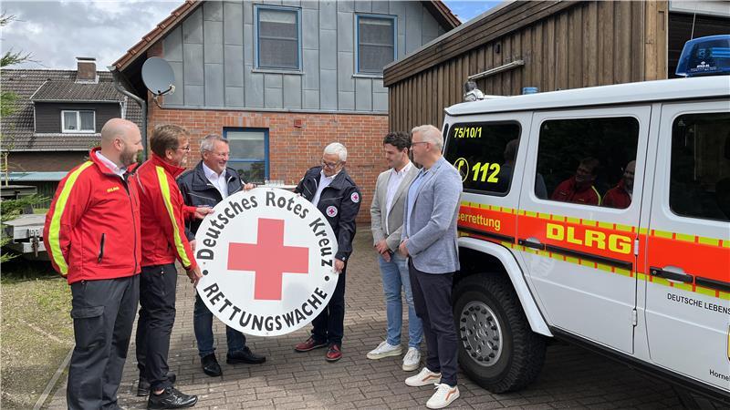 Abgebaut: Käufer Rainer Bohmbach (DLRG) übergibt das Schild der Rettungswache bei der Übergabe der Immobilie an Uwe Lütjen und Michael Roesberg vom Roten Kreuz (von links). Robert Rink, Julian Dubbels und Samtgemeindebürgermeister Knut Willenbockel schauen zu.