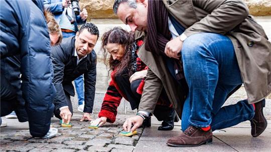 Abgeordnete der demokratischen Fraktionen reinigen Stolpersteine vor dem Hamburger Rathaus.