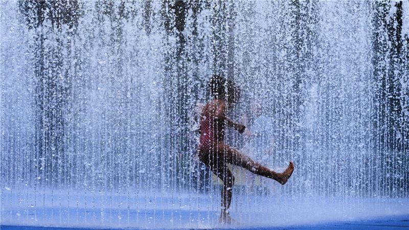 Abkühlung: Ein Kind spielt in einem Springbrunnen in London, während ungewöhnliche Hitze in der britischen Hauptstadt herrscht.