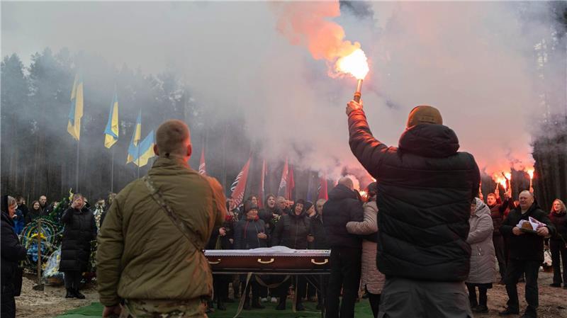 Abschied: Menschen zünden auf dem Friedhof von Slawuta in der Ukraine Fackeln während der Abschiedszeremonie für einen ukrainischen Soldaten. Der junge Mann war erst 18, als er im Ukraine-Krieg getötet wurde