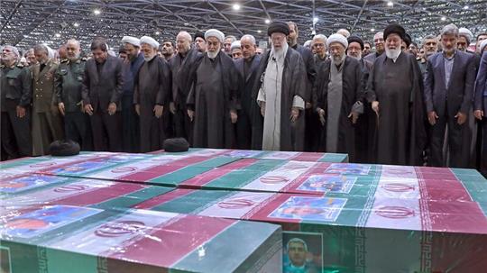 Abschied von Präsident Ebrahim Raisi, Außenminister Hussein Amirabdollahian und den weiteren beim Hubschrauberabsturz Getöteten: Irans Religionsführer Ajatollah Ali Chamenei (M.r.) spricht in Teheran an den mit Flaggen bedeckten Särgen ein Gebet.