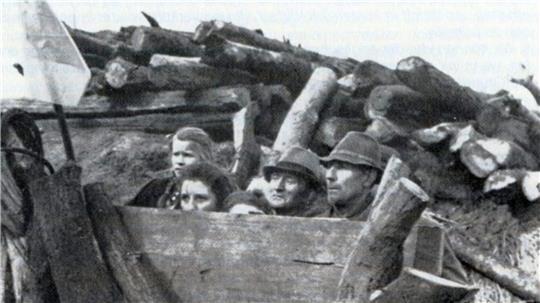 Ängstlich-sketische Blicke: Hinter Holzstämmen verborgen warteten Menschen auf den Einmarsch der alliierten Truppen. Der Schnappschuss stammt von einem britischen Kriegsberichterstatter.