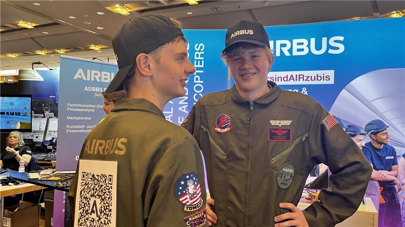 Werben um Azubis: Wenn Top Gun plötzlich im Stadeum auftaucht Airbus wirbt mit Top-Gun-Overalls: Die Azubis Luca und Tjorben haben sie für die Messe angelegt und einen QR-Code auf dem Rücken.