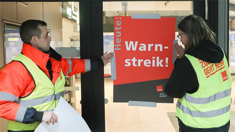 Warnstreik am Flughafen hat begonnen – Keine Starts ab Hamburg Airport-Mitarbeiter bringen zu Streikbeginn am Flughafen Hamburg ein Plakat mit der Aufschrift „Warnstreik“ an. Foto: Bodo Marks/dpa