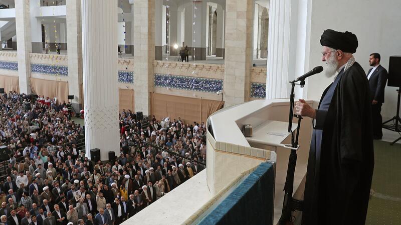 Ajatollah Ali Chamenei hält bei seiner Rede den Lauf eines Gewehrs in der Hand.