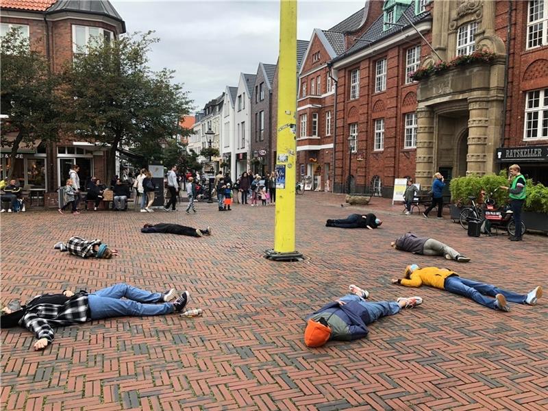 Aktive der Fridays-for-Future-Ortsgruppe liegen auf dem Buxtehuder Rathausplatz. Sie inszenieren ein „Die-In“, eine Protestform, bei der sie sich tot stellen, um auf das das existenzielle Ausmaß der Klimakrise hinzuweisen. Foto: Paula Golin