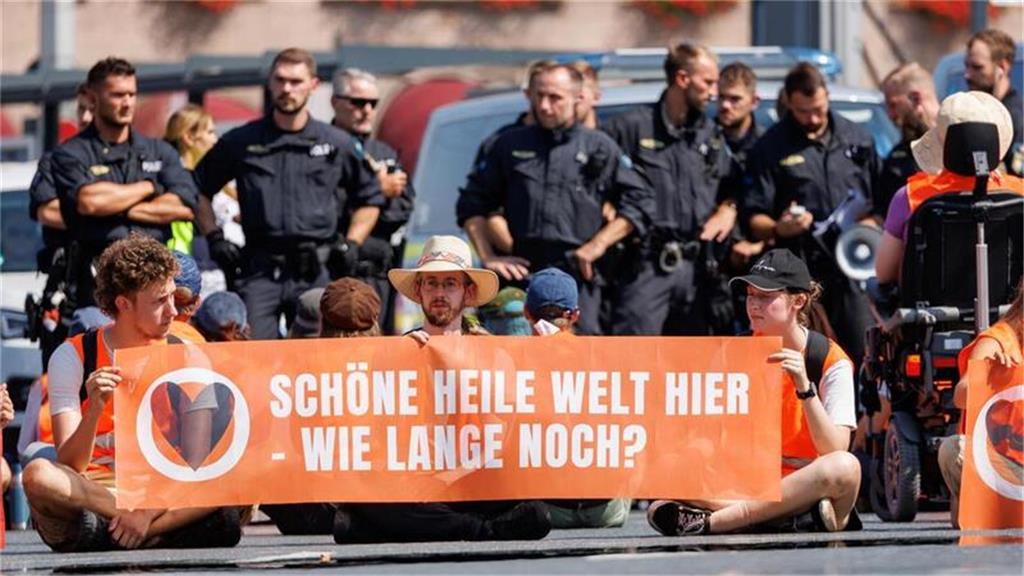 Aktivisten der Klimaschutzorganisation Letzte Generation protestieren mit einem ...