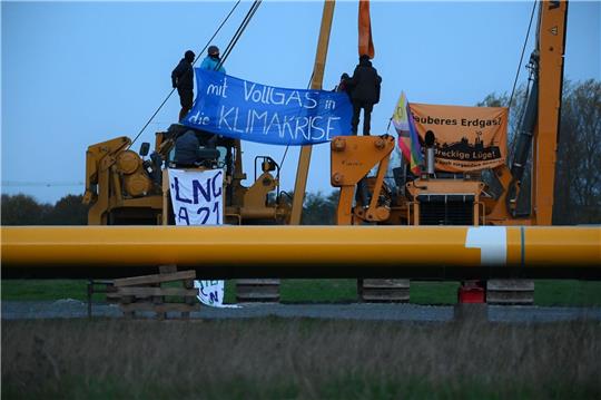 Aktivisten sitzen auf Baufahrzeugen und haben Plakate mit der Aufschrift "mit Vollgas in die Klimakrise" und "Sauberes Erdgas? Eine dreckige Lüge" gespannt. Foto: dpa/Jonas Walzberg
