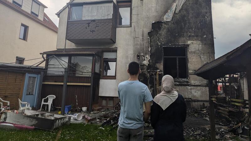 Alaa Alzubia und seine Mutter Bdour Alsayed stehen vor den Trümmern des abgebrannten Wintergartens. Seit dem Feuer ist ihre Wohnung unbewohnbar.