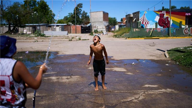 Alejo Quiroga fängt Wasser aus einem Schlauch, um sich wegen der hohen Temperaturen am Stadtrand von Buenos Aires abzukühlen.