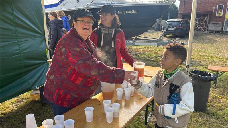 Ahlerstedter Kinder helfen: Wenn tonnenweise Äpfel zu Saft werden Alexa Treisch (links) schenkte den warmen Apfelsaft aus.