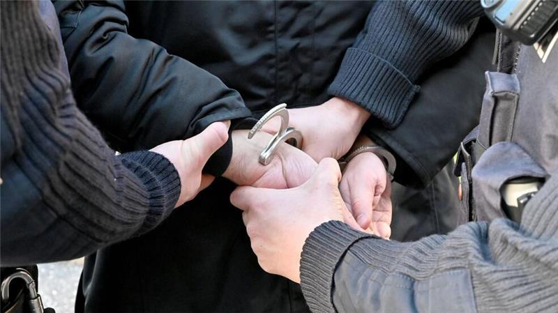 Einem Mann werden von zwei Polizisten Handschellen angelegt.