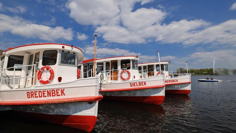 Alsterschiffe liegen bei strahlendem Sonnenschein am Jungfernstieg.