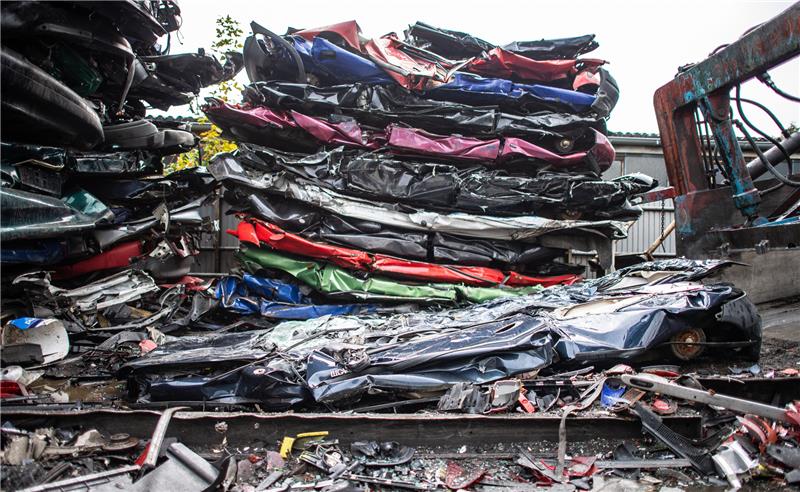 Alte Schrottautos liegen zusammengedrückt und übereinandergestapelt bei einem Autoverwerter, nachdem sie aus einer Schrottpresse geschoben wurden. Foto: Guido Kirchner/dpa