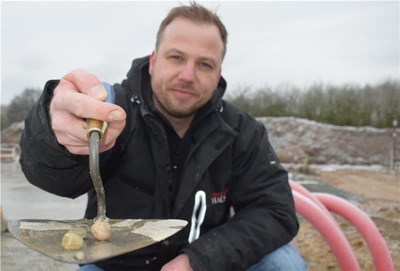 Alter Baustoff für modernste Häuser: Bauleiter Lars Möller zeigt, was im Smart-City-Zauberbeton steckt, der die CO 2 -Emission des Betons in der Bodenplatte um die Hälfte senkt. Noch gut zu erkennen sind die kleinen Steine, die als ungelieb