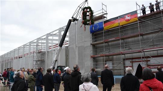 Am Bau beteiligte Repräsentanten von Firmen, Behörden und Bundeswehr verfolgen den Richtspruch an dem zweigeschossigen Hauptgebäude mit Anbau. Foto: Hilken