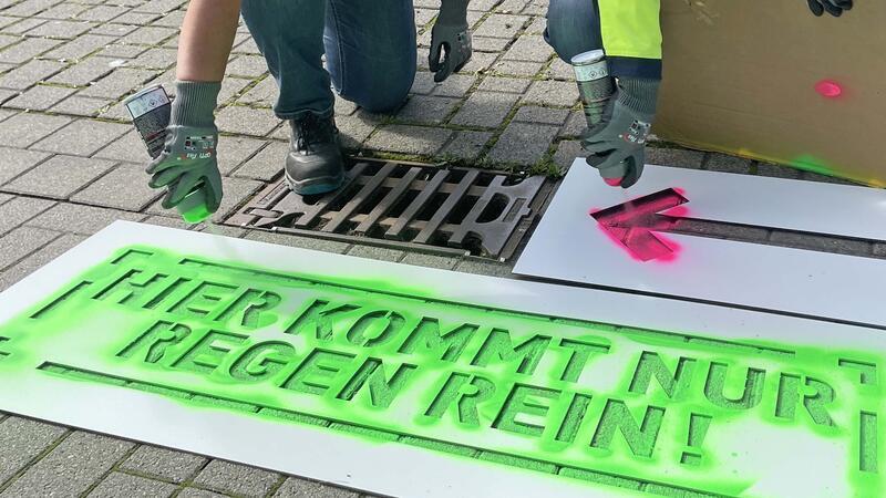 Am Busbahnhof hat der erste Gully seine Botschaft erhalten: "Hier kommt nur Regen rein" steht in grüner Farbe auf dem Straßenpflaster.