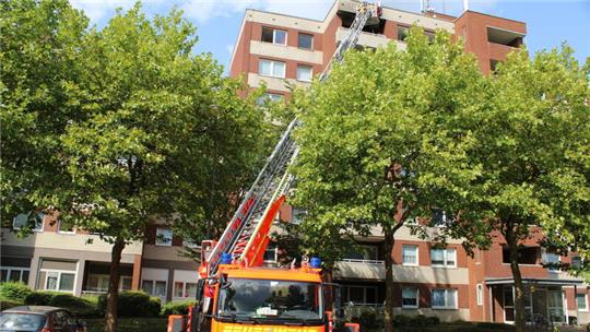 Eine Drehleiter steht vor einem Wohnhaus.