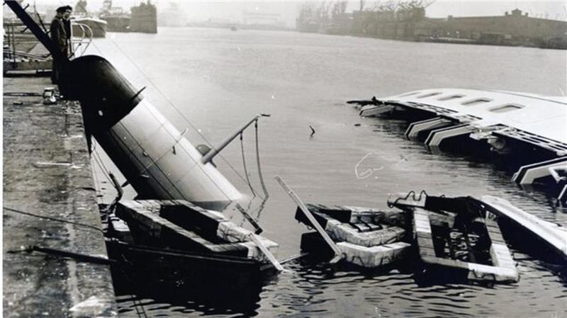 Am Morgen nach dem Unglück gluckerte es noch im Rumpf des Schiffs. Rettungsflöße schwammen im Wasser, und der abgeknickte Schornstein lehnte an der Kajenmauer Unter den nun waagerechten Fenstern des Hauptdecks leuchtete das Rot der Schwimmwesten, die unter den Fenstern im Inneren der "Bremerhaven" im Wasser dümpelten.