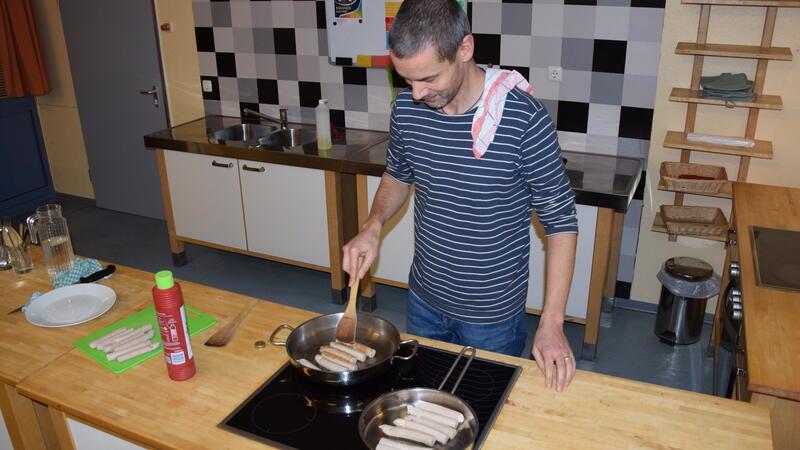 Am Sandalismus-Abend brät der stellvertretende VHS-Leiter Tobias Rothenberg Würste für die Besucher. Bratwurst gilt als Mittel, Männer in die Volkshochschule zu locken.