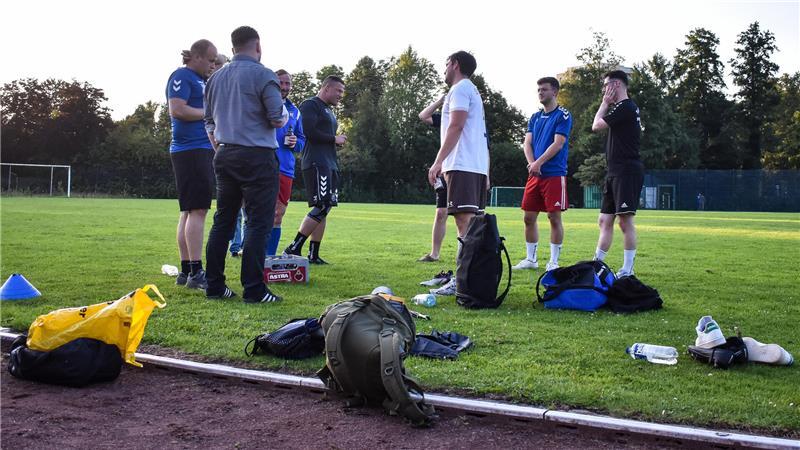 Ein Kreis von Spielern steht nach dem Training zusammen, trinkt etwas zusammen und redet.