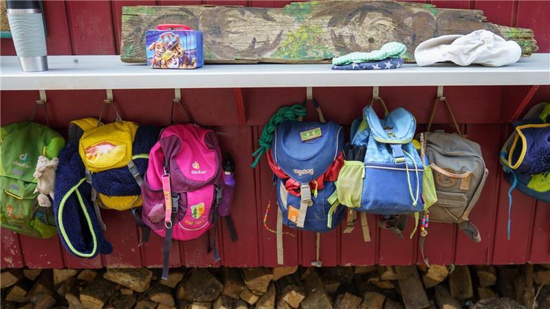 An einem Bauwagen hängen die Kinder eines Waldkindergartens ihre Rucksäcke auf.